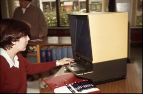old photo of someone using a microfilm reader