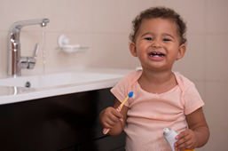 child holding toothbrush and toothpaste