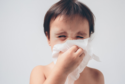 child sneezing into tissue