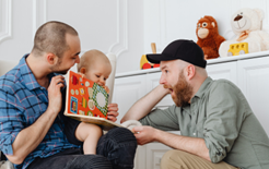 adults reading book to baby